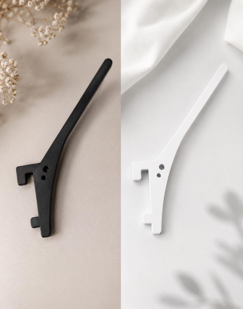 May include: A set of two elongated, curved hooks, one in matte black and one in matte white. Each hook features a long, tapered arm, a flat mounting base with two circular screw holes, and two distinct, squared-off prongs extending outward.