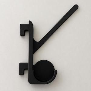 May include: A matte black wall hook featuring a vertical spine with two rectangular mounting brackets on the left side, a circular base plate, and a long, angled arm extending upward to the right for hanging items.