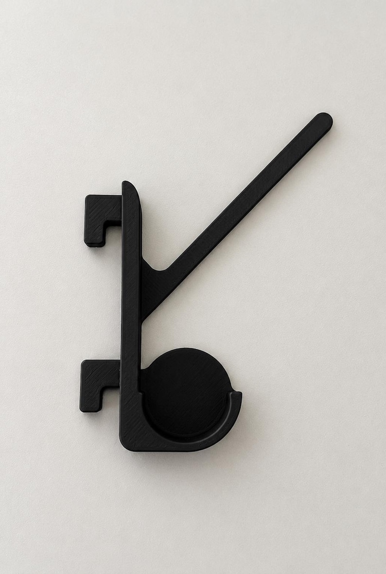 May include: A matte black wall hook featuring a vertical spine with two rectangular mounting brackets on the left side, a circular base plate, and a long, angled arm extending upward to the right for hanging items.