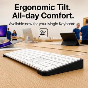 May include: A white Magic Keyboard resting on a black angled stand. The text reads: Ergonomic Tilt. All-day Comfort. Available now for your Magic Keyboard. A small icon shows a hand resting on a keyboard with a downward arrow indicating tilt.