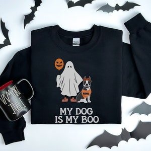May include: Black sweatshirt with a ghost holding a jack-o-lantern balloon and a dog wearing a headband and a name tag that says "NAME". The text on the sweatshirt says "My dog is my boo."