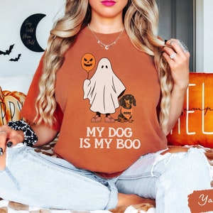 a woman sitting on a bed wearing a t - shirt that says my dog is