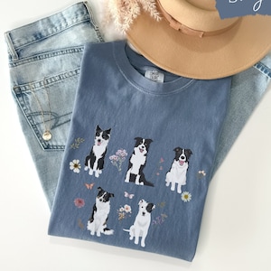 May include: A blue jean t-shirt with a graphic of five border collies and flowers. The shirt has the text "Comfy Colors" on the tag.