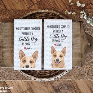 two white washcloth towels with a picture of a dog on them, placed on a wooden surface.