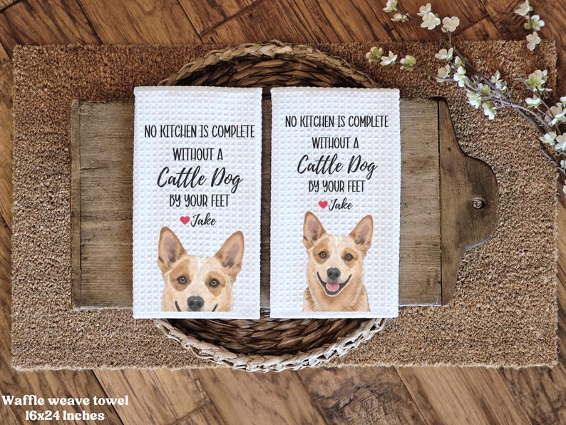 two white washcloth towels with a picture of a dog on them, placed on a wooden surface.