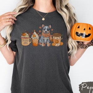 May include: A dark gray t-shirt with a blue heeler dog, pumpkin spice latte, and a pumpkin spice coffee cup graphic. The text on the latte cup says "Pumpkin Spice".