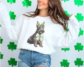 Puede incluir: Sudadera blanca con un terrier escocés negro y marrón que lleva una pajarita verde de trébol. El perro lleva una diadema verde de trébol.
