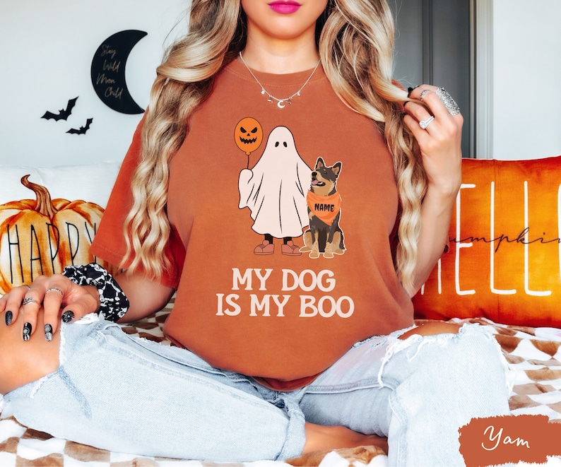 a woman sitting on a bed with a dog wearing a ghost shirt