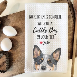 a kitchen towel with a dog image and text, along with some kitchen utensils such as a rolling pin and a wooden spoon.