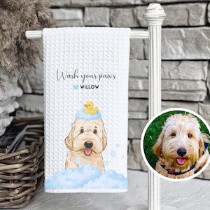 May include: White waffle-weave towel with a watercolor illustration of a dog wearing a rubber ducky on its head, surrounded by blue bubbles. Text reads "Wash your paws" and "Willow". A circular photo of a dog is on the right.