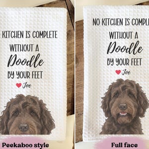 two towels with a dog's face on them. The towels are labeled with a humorous message about a kitchen and a dog.