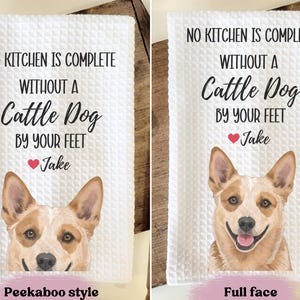 two towels with a humorous message about having a cattle dog by one's feet. The towels feature a cartoon image of a dog's face and the text "NO KITCHEN IS COMPLETE WITHOUT A Cattle Dog BY YOUR FEET Jake" along with the text "Peekaboo style" and "Full face" indicating the style of the towel.