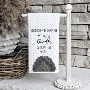 a towel with a dog on it, hanging on a white towel holder.