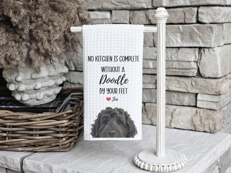 a towel with a dog on it, hanging on a white towel holder.