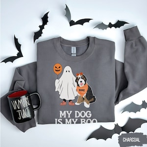 May include: Charcoal gray sweatshirt with a ghost and a dog dressed as a ghost for Halloween. The text on the sweatshirt says "My dog is my boo".