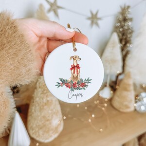 a person holding a christmas ornament with a dog on it