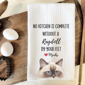 May include: White kitchen towel with a Ragdoll cat illustration and the text "No kitchen is complete without a Ragdoll by your feet" with a red heart and the name "Mochi" underneath.