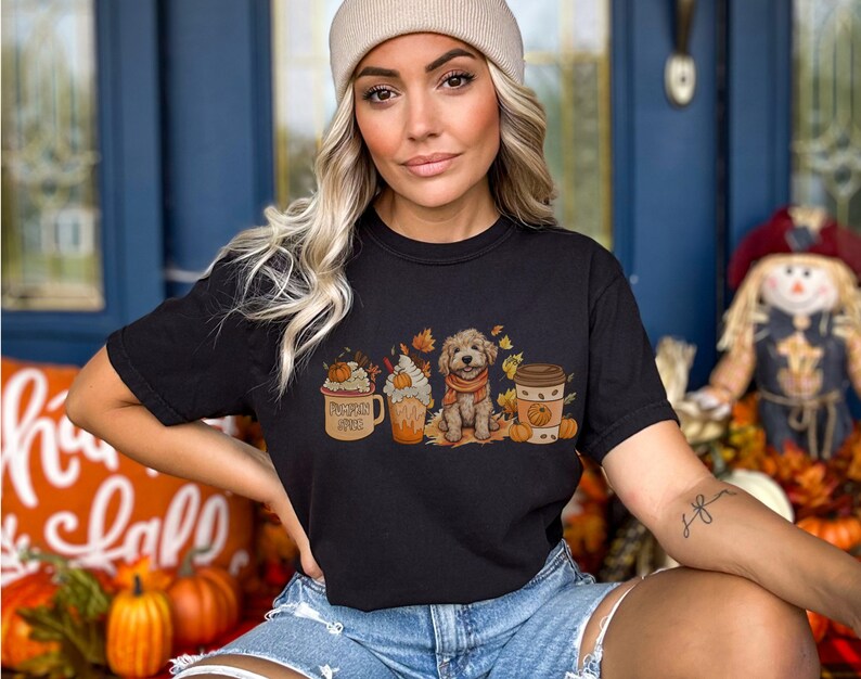 a woman wearing a black t - shirt with a picture of cats and pumpkins