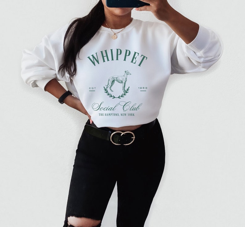 Puede incluir: Sudadera blanca recortada con un gr&aacute;fico verde de un perro whippet y el texto "Whippet Social Club Est. 1993 The Hamptons, New York"