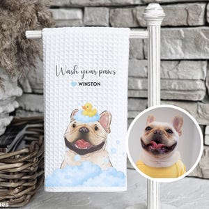 May include: White waffle-weave towel with a cartoon French Bulldog in blue bubbles and a rubber ducky on its head. Text reads "Wash your paws" and "Winston". The towel measures 16x24 inches.