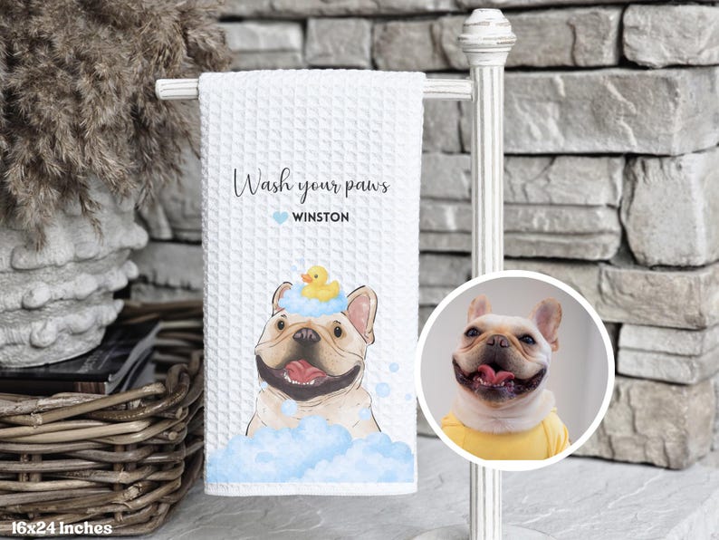 May include: White waffle-weave towel with a cartoon French Bulldog in blue bubbles and a rubber ducky on its head. Text reads "Wash your paws" and "Winston". The towel measures 16x24 inches.
