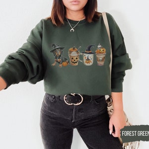 a woman wearing a green sweatshirt with halloween pictures on it