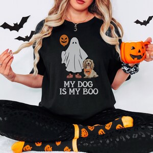 a woman in a black shirt is holding a pumpkin