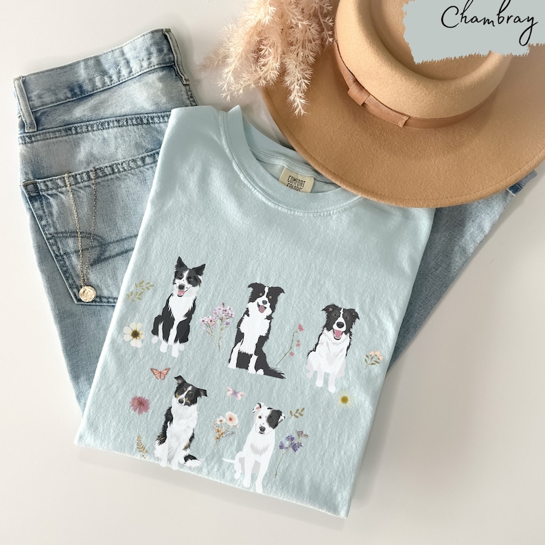 May include: A light blue t-shirt with a graphic of five black and white border collies surrounded by flowers and butterflies. The text "CONTEST READY" is printed on the shirt.