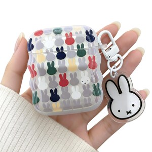 May include: A clear AirPod case decorated with a pattern of colourful bunny silhouettes. The case has a white metal clip and a clear charm with a white bunny face. The bunny silhouettes are in various colours, including red, green, and yellow.