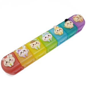 May include: A colorful weekly pill organizer with seven compartments, each a different color of the rainbow. Each compartment is decorated with a cute cartoon animal. The pill box is designed to help organize medications.