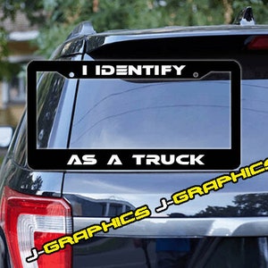 May include: Black and white license plate frame with the text "I Identify As A Truck".