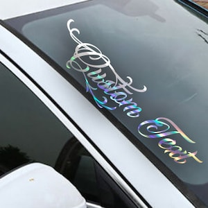 May include: A silver iridescent car window decal with the text "Custom Text" in a cursive font.