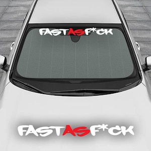 May include: White car with a windshield sunshade that says "FAST AS F*CK" in red and white lettering. The same phrase is also written on the hood of the car in white lettering with the word "AS" in red.