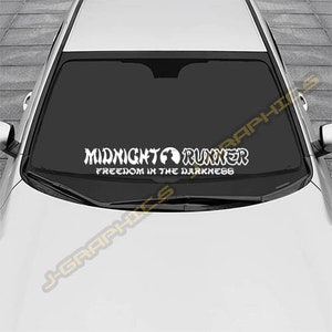 May include: White vinyl decal for a car windshield. The decal says "Midnight Runner" with a globe symbol and the words "Freedom in the Darkness".
