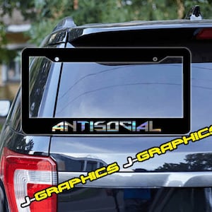 Puede incluir: Marco de matrícula negro con la palabra "ANTISOCIAL" en un acabado arcoíris iridiscente. El marco está en un coche negro.