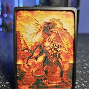 May include: A rectangular 3D printed plaque featuring a textured relief of a feathered serpent deity standing before a stepped pyramid. The artwork uses a vibrant color palette of deep red, orange, yellow, and green, all encased in a black frame.