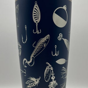 May include: Navy blue insulated tumbler with a stainless steel rim and lid. The tumbler is decorated with etched fishing lures, hooks, and a bobber. The design is repeated around the entire surface of the tumbler.