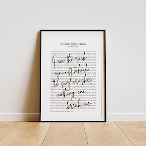 May include: A framed print with black frame. The print features text from "A Court of Silver Flames" with the quote "I am the rock against which the surf crashes. Nothing can break me." The background is white.