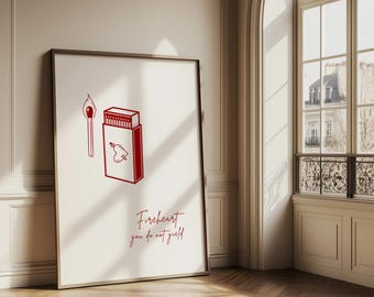 Puede incluir: Impresión artística enmarcada con una ilustración roja de una cerilla encendida y una caja de cerillas con un diseño de corazón. El texto "Fireheart you do not yield" está escrito en rojo debajo. La obra de arte se exhibe en una habitación con una gran ventana.