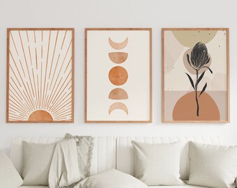 May include: Three framed prints with abstract designs in shades of brown and beige. The left print features a sunburst design, the middle print features a series of moons in different phases, and the right print features a stylized flower with a brown background.