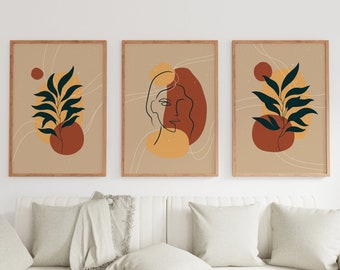 May include: Set of three abstract art prints with a beige background, featuring a stylized face, a leafy branch, and a leafy branch with a red circle. The prints are framed in a light wood frame.