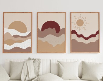 May include: Three abstract art prints with a desert landscape theme. The prints feature a sunset with a red sun, a sunset with a yellow sun, and a sun with rays. The prints are framed in natural wood frames.