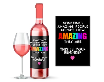 Può includere: Una bottiglia di vino con un'etichetta nera che dice "A volte le persone incredibili dimenticano quanto sono incredibili. Questo è il tuo promemoria." L'etichetta ha un design arcobaleno e un cuore rosa.