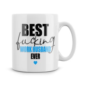 May include: White ceramic coffee mug with black text that reads "BEST fucking WORK HUSBAND EVER" with a blue heart.