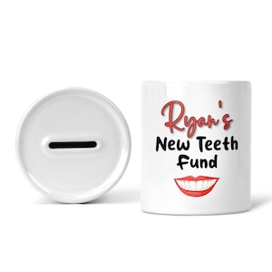 May include: White ceramic piggy bank with a slot on the top. The front of the bank has the text "Ryan's New Teeth Fund" in black with a red smiling mouth graphic.