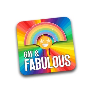 May include: A square coaster with a rainbow design and a smiling cartoon face holding up a rainbow. The text "Gay & Fabulous" is printed in white on the coaster.