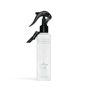 Puede incluir: Botella de spray para el hogar rectangular blanca con una boquilla de pulverización negra y una etiqueta negra que dice "LONDON". La botella tiene el texto "THE ESSENCE LONDON" y "Leathery Vanilla". La parte inferior de la botella dice "Luxury Home Spray" y "e 300 ml / 10.14 fl oz."