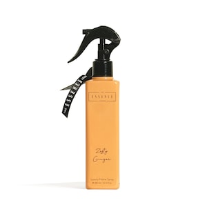 May include: A rectangular, amber-colored home spray bottle with a black spray nozzle and a black tag that reads "THE ESSENCE LONDON." The bottle is labeled "Zesty Ginger" and "Luxury Home Spray." The bottle contains 300 ml / 10.14 fl oz.