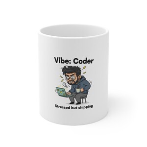 Può includere: Tazza in ceramica bianca con la scritta "Vibe: Coder" e un'illustrazione di un programmatore stressato con un laptop e un caffè. Il testo "Stressed but shipping" è sotto.