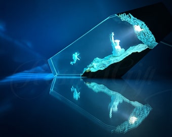 May include: A clear glass sculpture with a blue glow, featuring a miniature Statue of Liberty and a figure falling from the sky. The sculpture is set against a dark blue background.